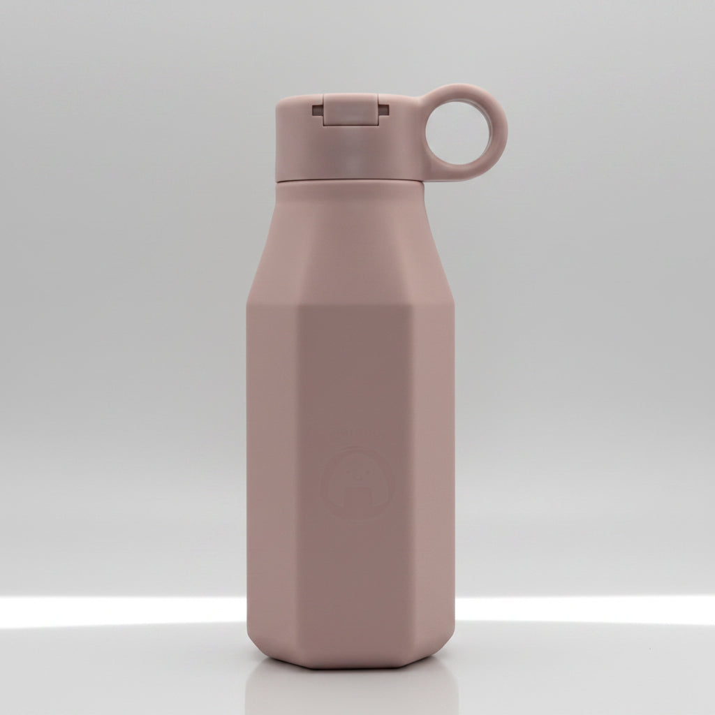 A pale mauve silicone water bottle with a pastel color, displayed alongside floral decorations, emphasizing its eco-friendly and reusable attributes.