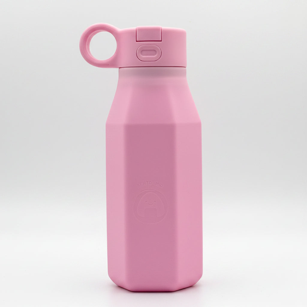 A pink silicone water bottle with a pastel color, displayed alongside floral decorations, emphasizing its eco-friendly and reusable attributes.