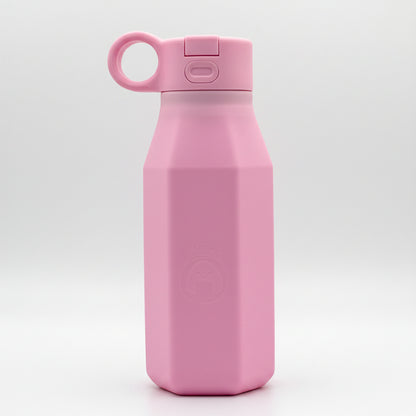 A pink silicone water bottle with a pastel color, displayed alongside floral decorations, emphasizing its eco-friendly and reusable attributes.
